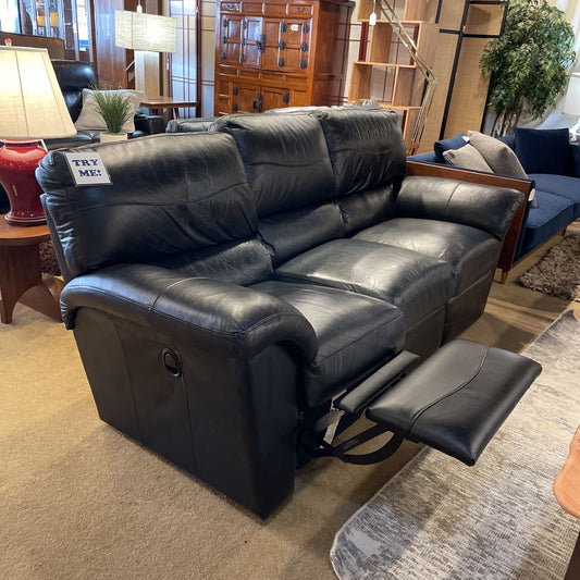 Black leather recliner sofa in a living room setting with furniture and decor.