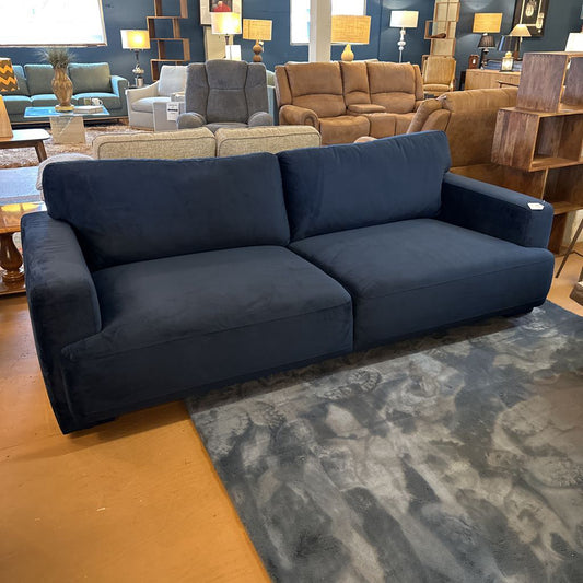 Blue sofa in a furniture store with other sofas and decor in the background.