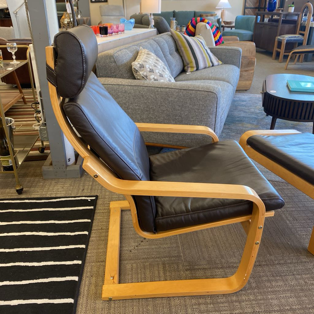 Modern chair with wooden frame and black leather seat in a living room setting.
