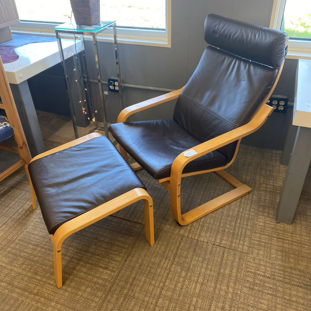 Leather chair and ottoman set in a room with tables and windows.