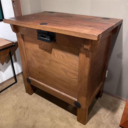 Wooden cabinet with a rectangular top and visible hardware on a carpeted floor.