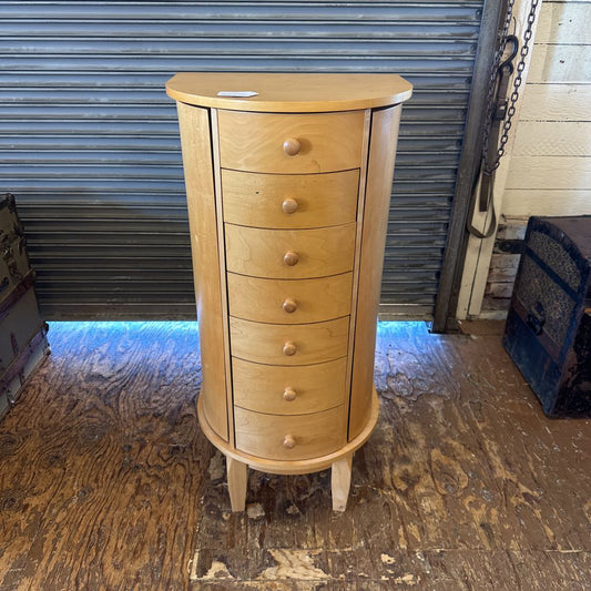Wooden jewelry cabinet with multiple drawers on a wooden floor.