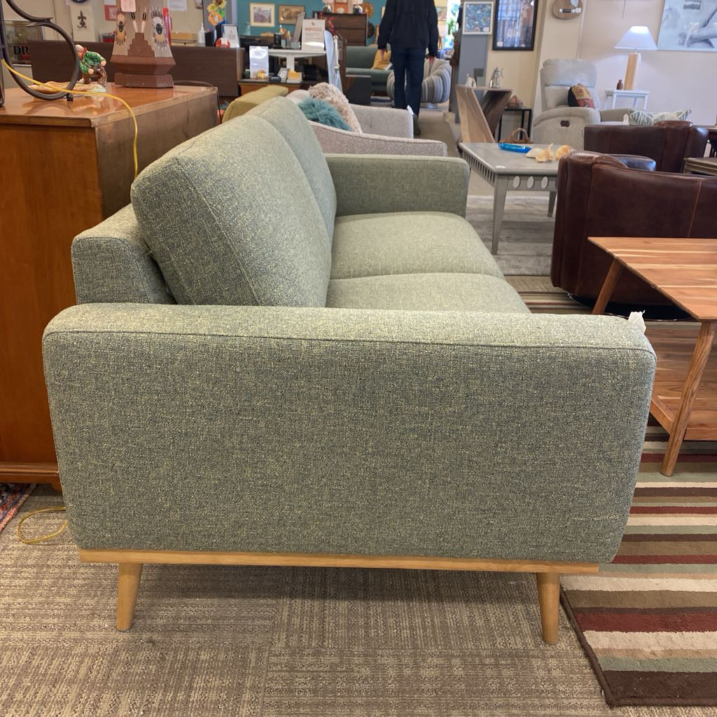 Green sofa in a furniture store with other furniture items in the background