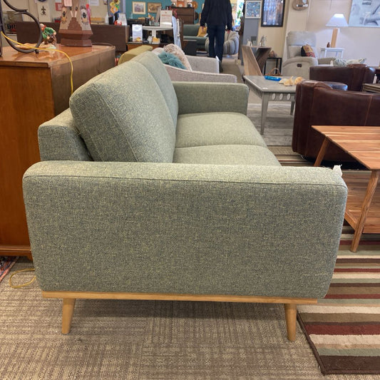 Green sofa in a furniture store with other furniture items in the background