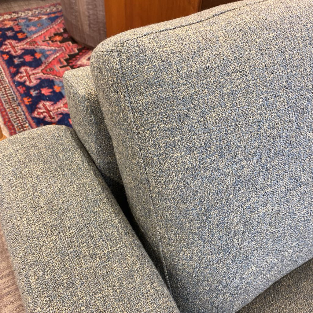 Close-up of a textured blue sofa with a patterned rug in the background