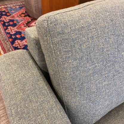 Close-up of a textured blue sofa with a patterned rug in the background