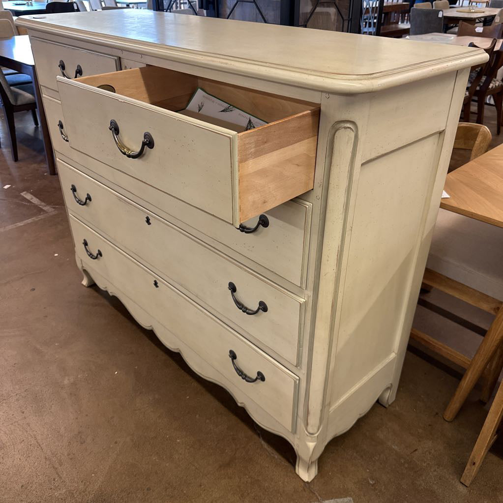 White dresser with open drawer in a room with tables and chairs