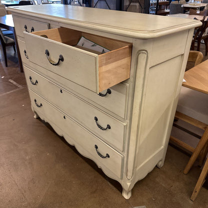 White dresser with open drawer in a room with tables and chairs