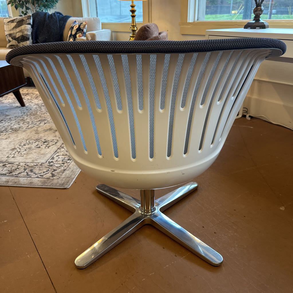 Modern chair with a white base and black cushion on a wooden floor.