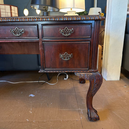 Wooden desk with ornate carvings on a wooden floor.
