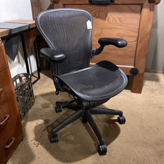 Black office chair in a room with wooden furniture and carpeted floor.