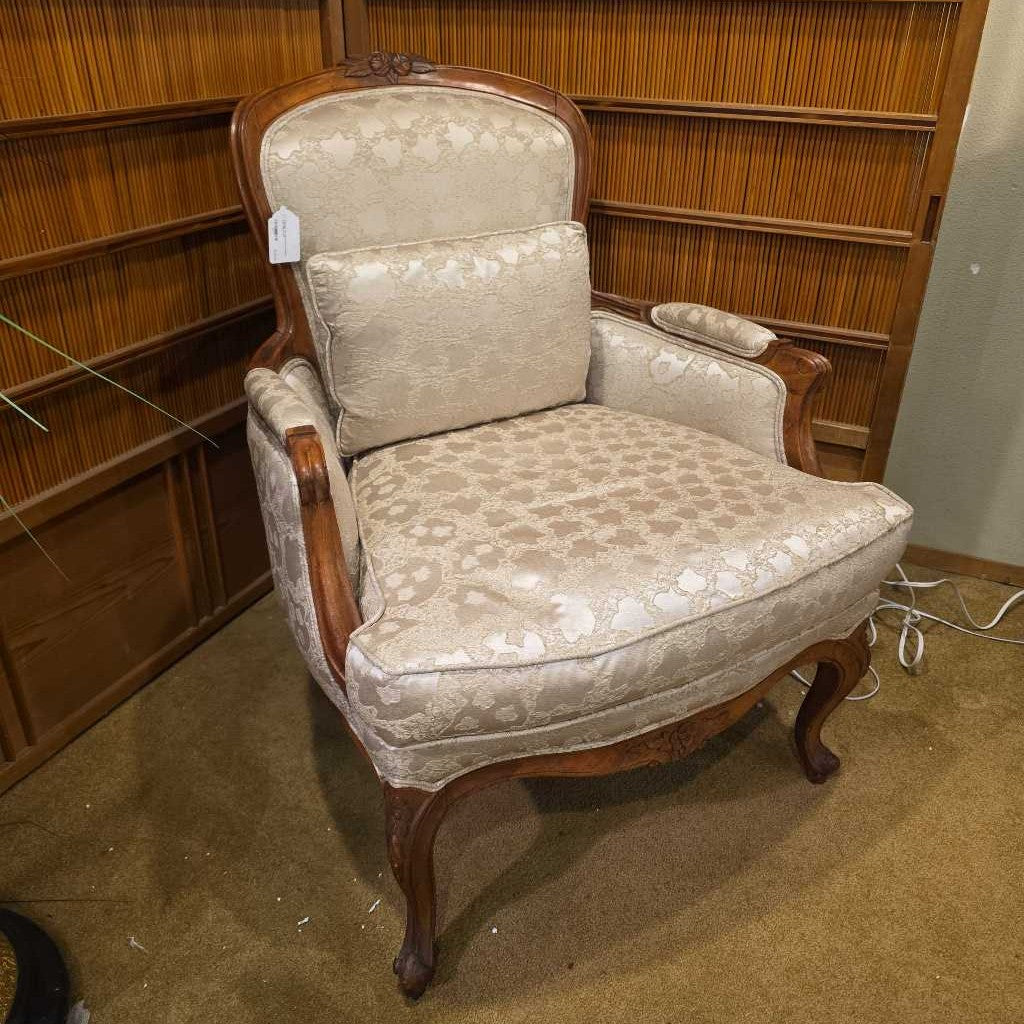 Vintage armchair with floral patterned cushions in a room with wooden shelves.