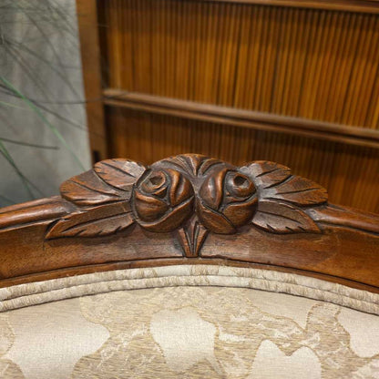 Close-up of an ornate wooden chair back with floral carvings.