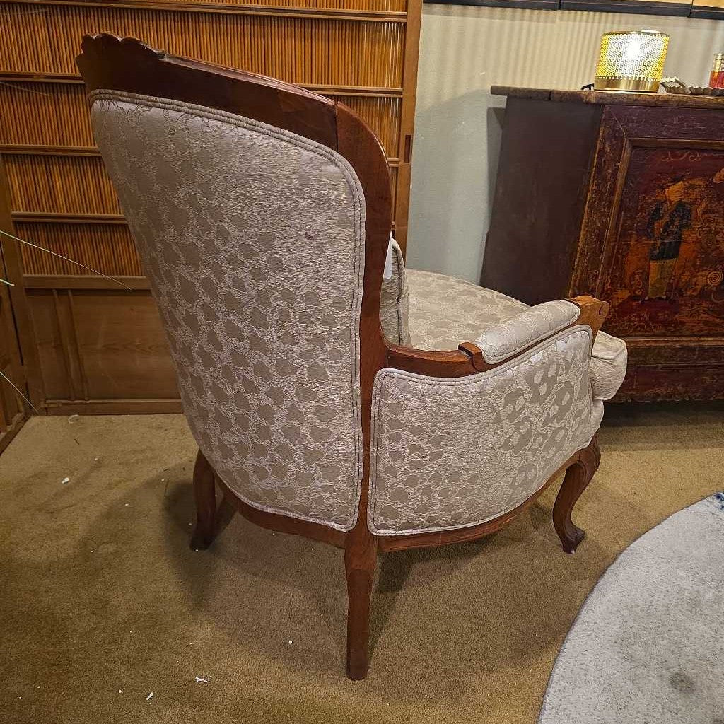 Vintage armchair with patterned backrest and wooden frame in a room setting.