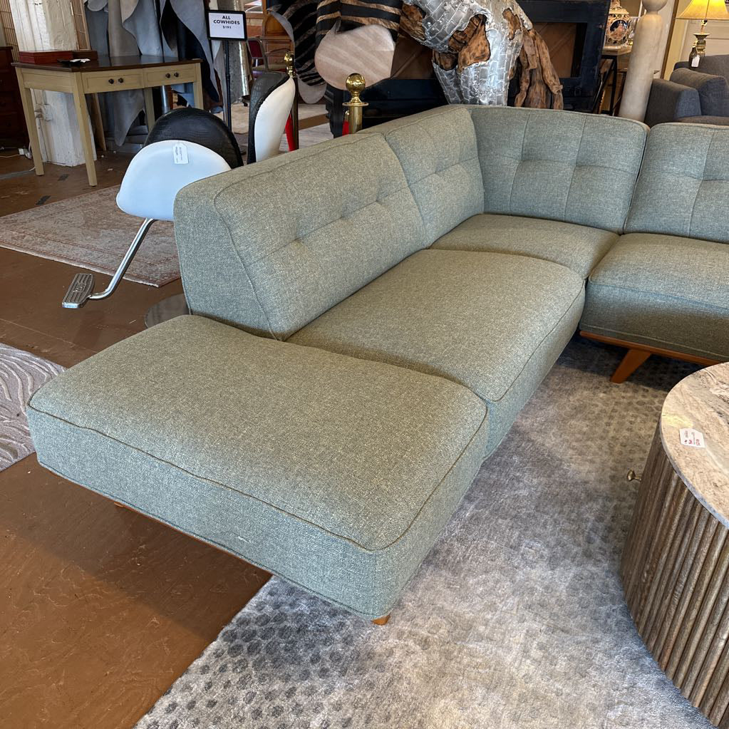 Gray sectional sofa in a showroom setting with other furniture items.
