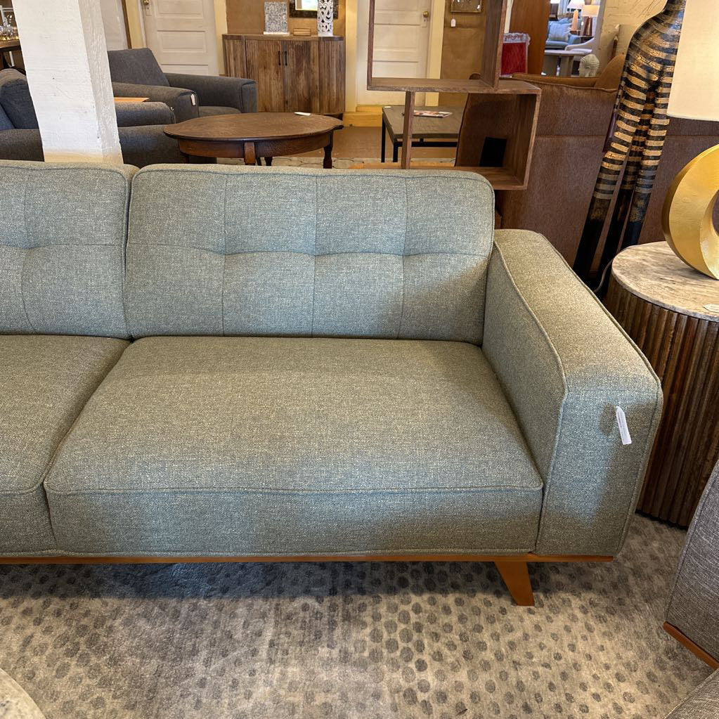 Gray sofa in a room with a patterned rug and furniture.