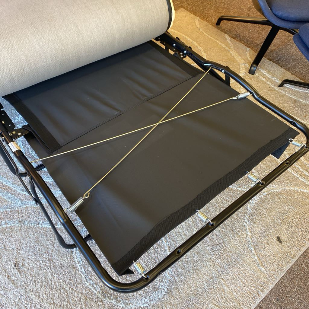 Foldable camping chair with a black seat on a textured floor.