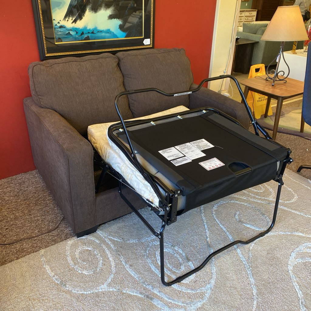 Foldable tray attached to a recliner chair in a room with a red wall and painting.