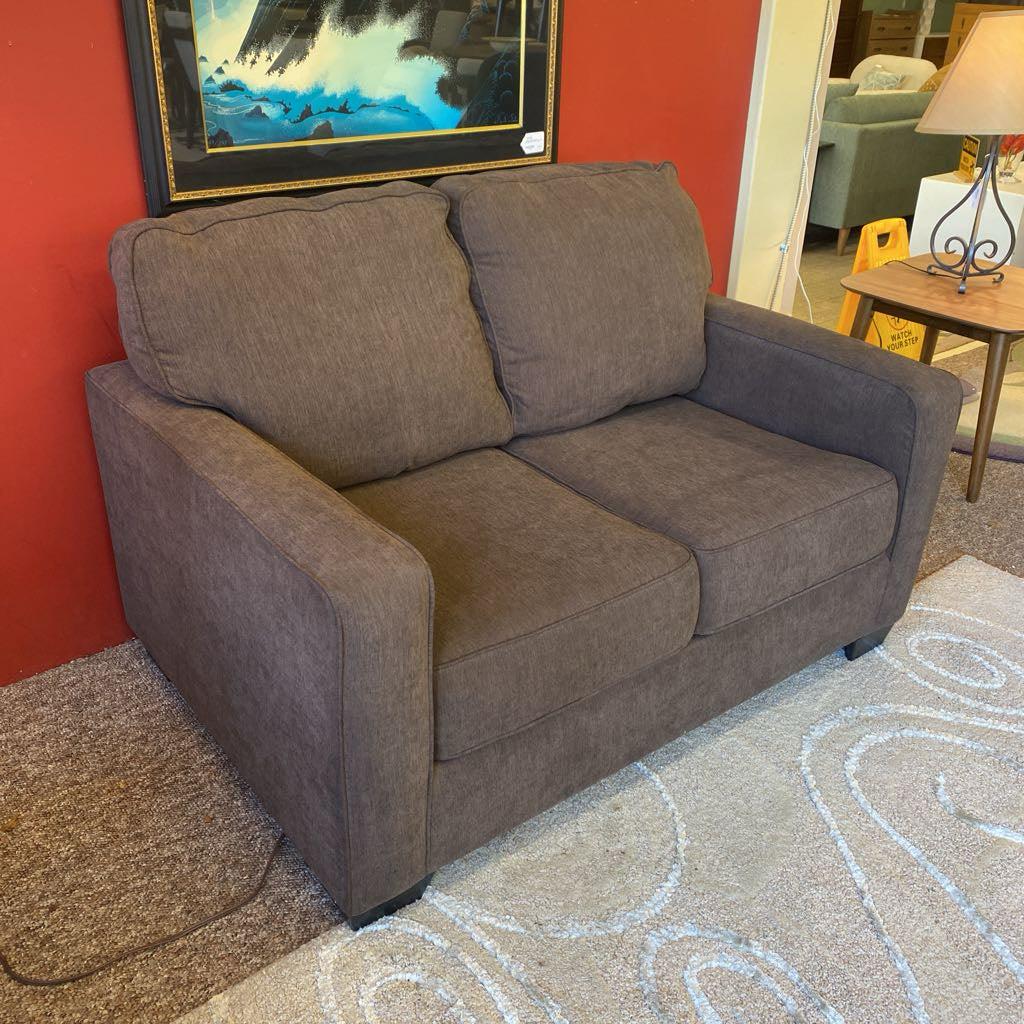 Gray sofa in a room with a red wall and a painting.