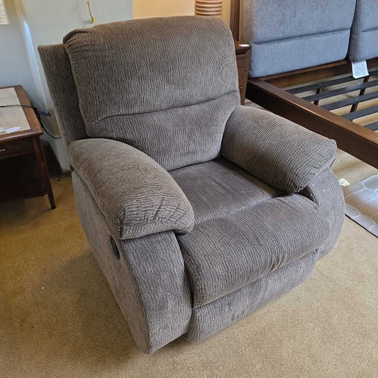 Gray recliner chair in a room with carpeted floor and furniture.