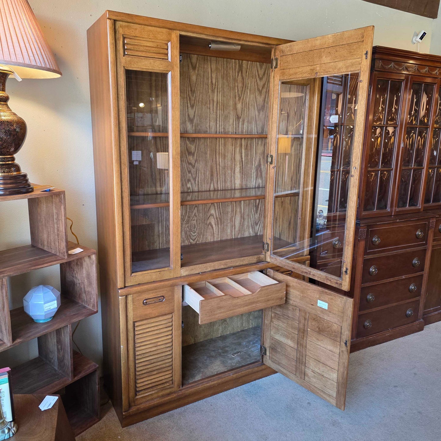Wooden display cabinet with glass doors on a beige floor.