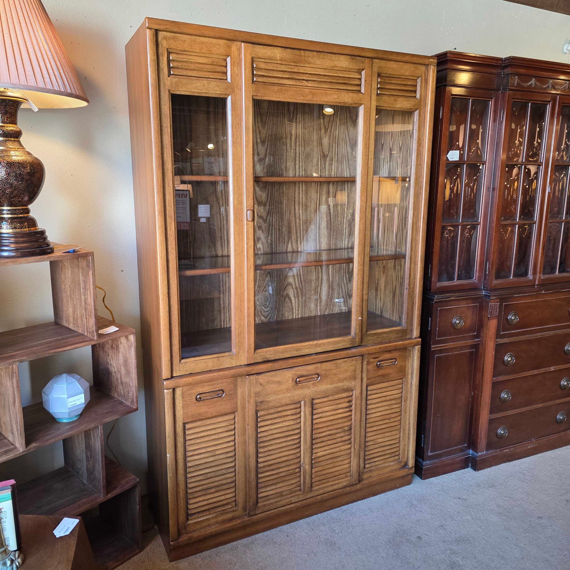 Wooden cabinet with glass doors and a lamp in the foreground