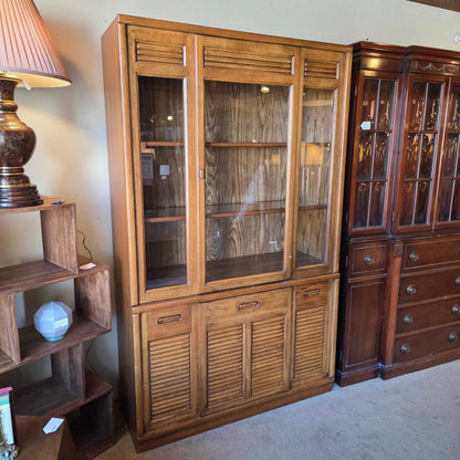 Wooden cabinet with glass doors and a lamp in the foreground