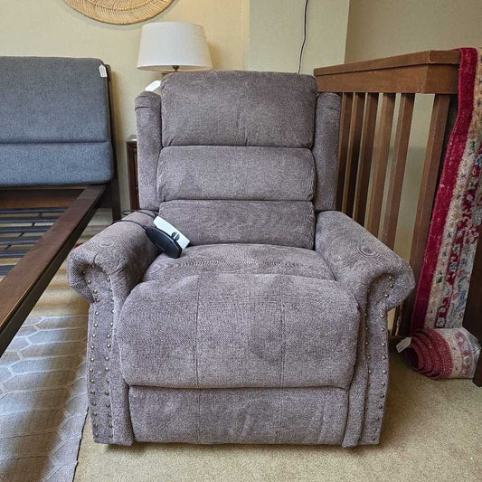 Gray recliner chair in a living room setting with a lamp and sofa.
