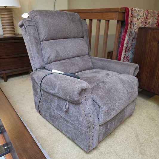 Gray recliner chair in a living room setting with wooden furniture and a lamp.