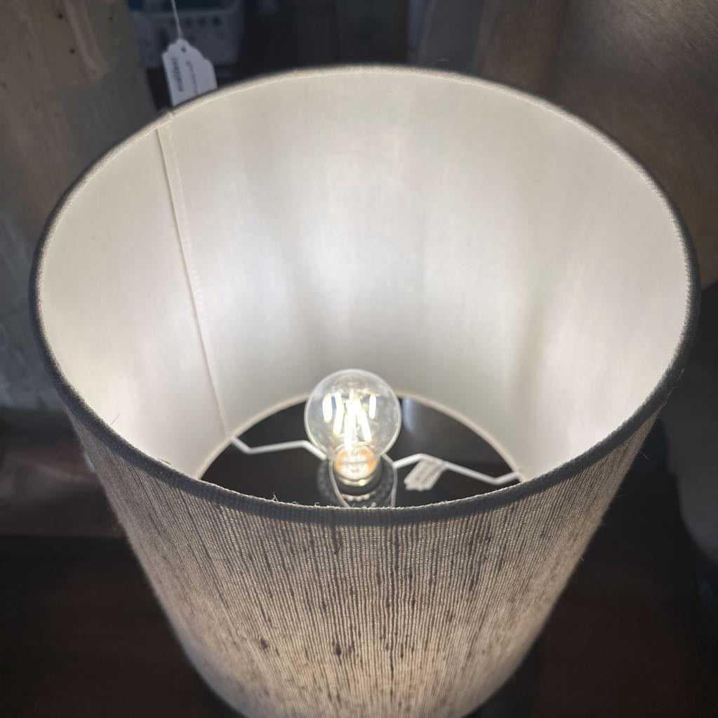 Lamp with a visible light bulb inside a textured lampshade.