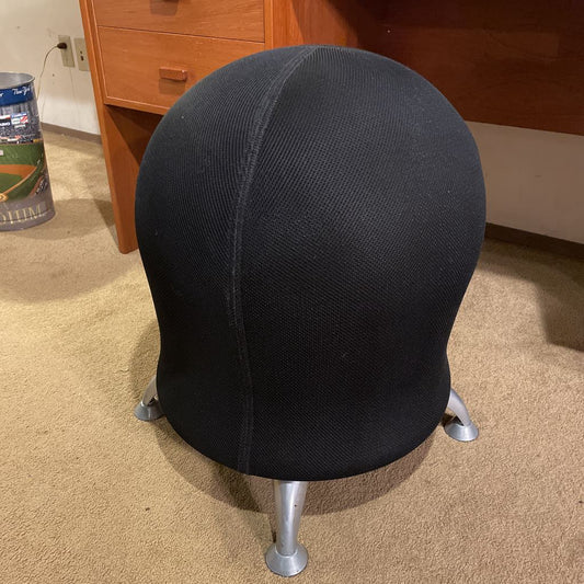 Black swivel chair on a carpeted floor with a wooden dresser in the background.