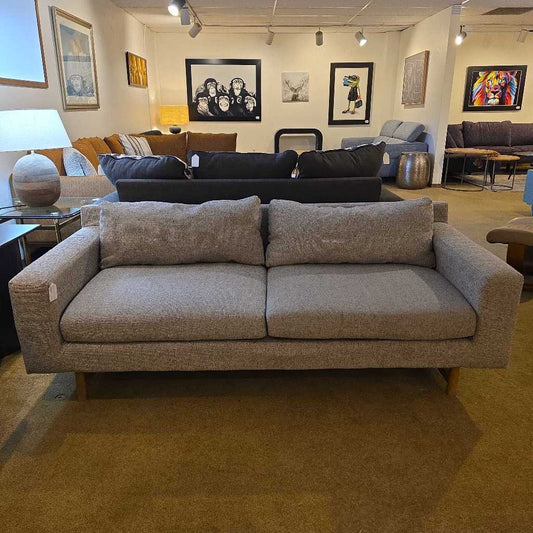 Gray sofa in a showroom with various decor items on the walls.