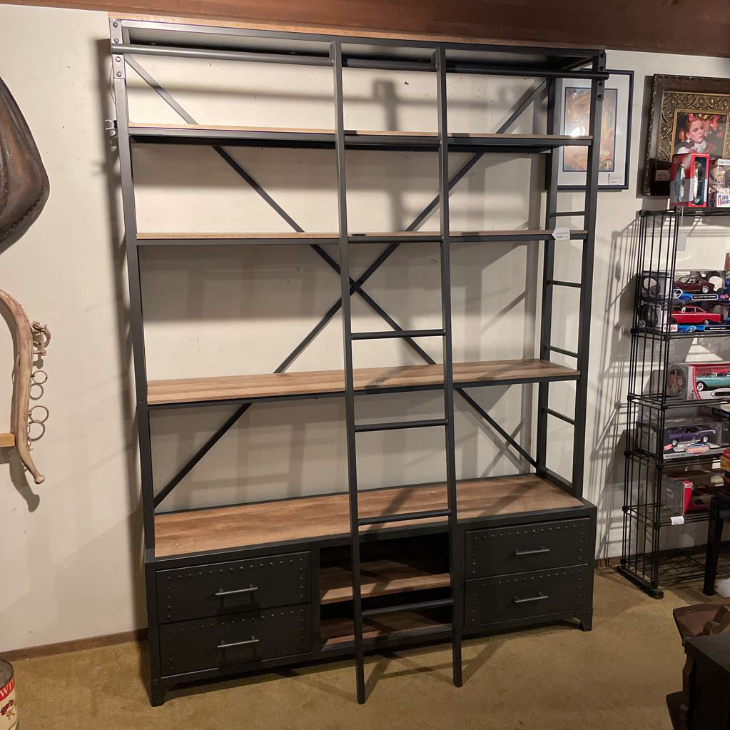 Industrial-style bookshelf with wooden shelves and metal accents in a room setting.