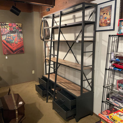 Bookshelf with ladder and storage drawers in a room with various items on shelves.