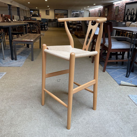 Wooden bar stool with woven seat in a showroom setting