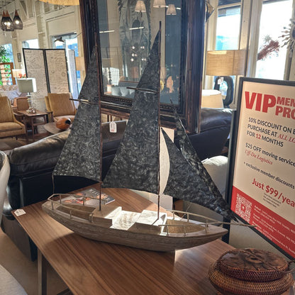 Model sailboat on a table with a promotional sign in the background