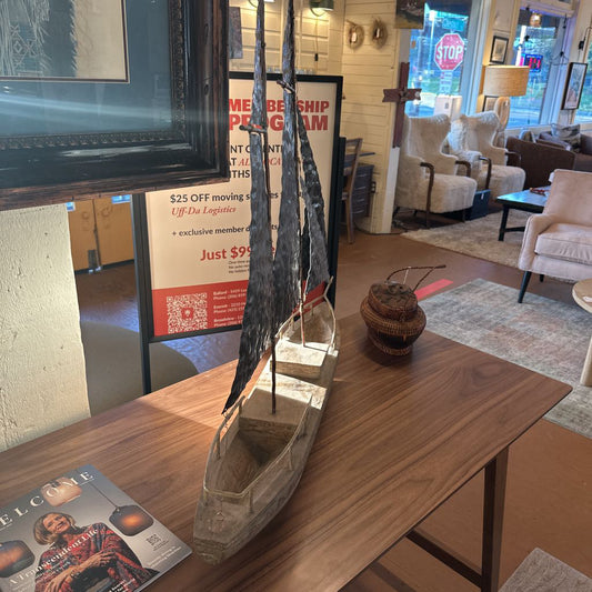 Model canoe on a wooden table with a store interior in the background
