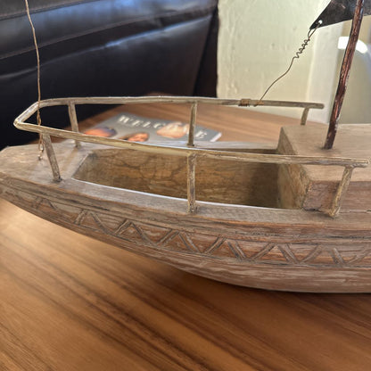 Wooden model boat on a wooden surface with a blurred background