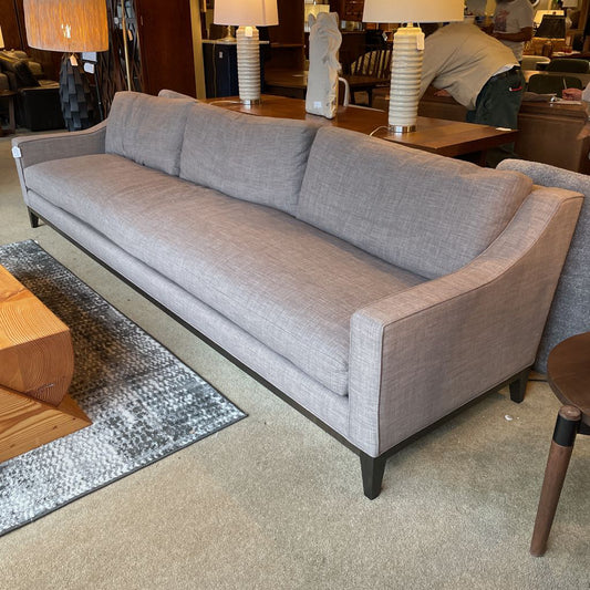 Gray sofa in a room with a rug and lampshades.