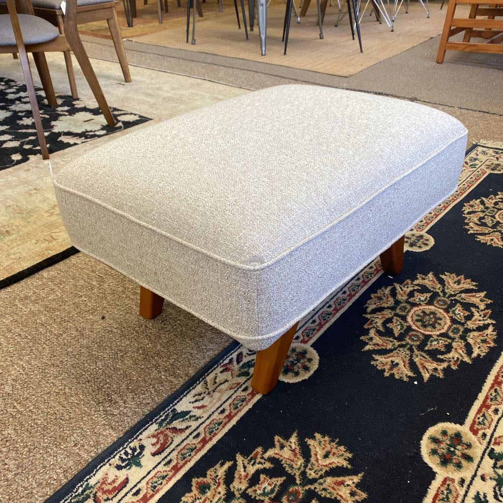 Gray textured ottoman on a patterned rug