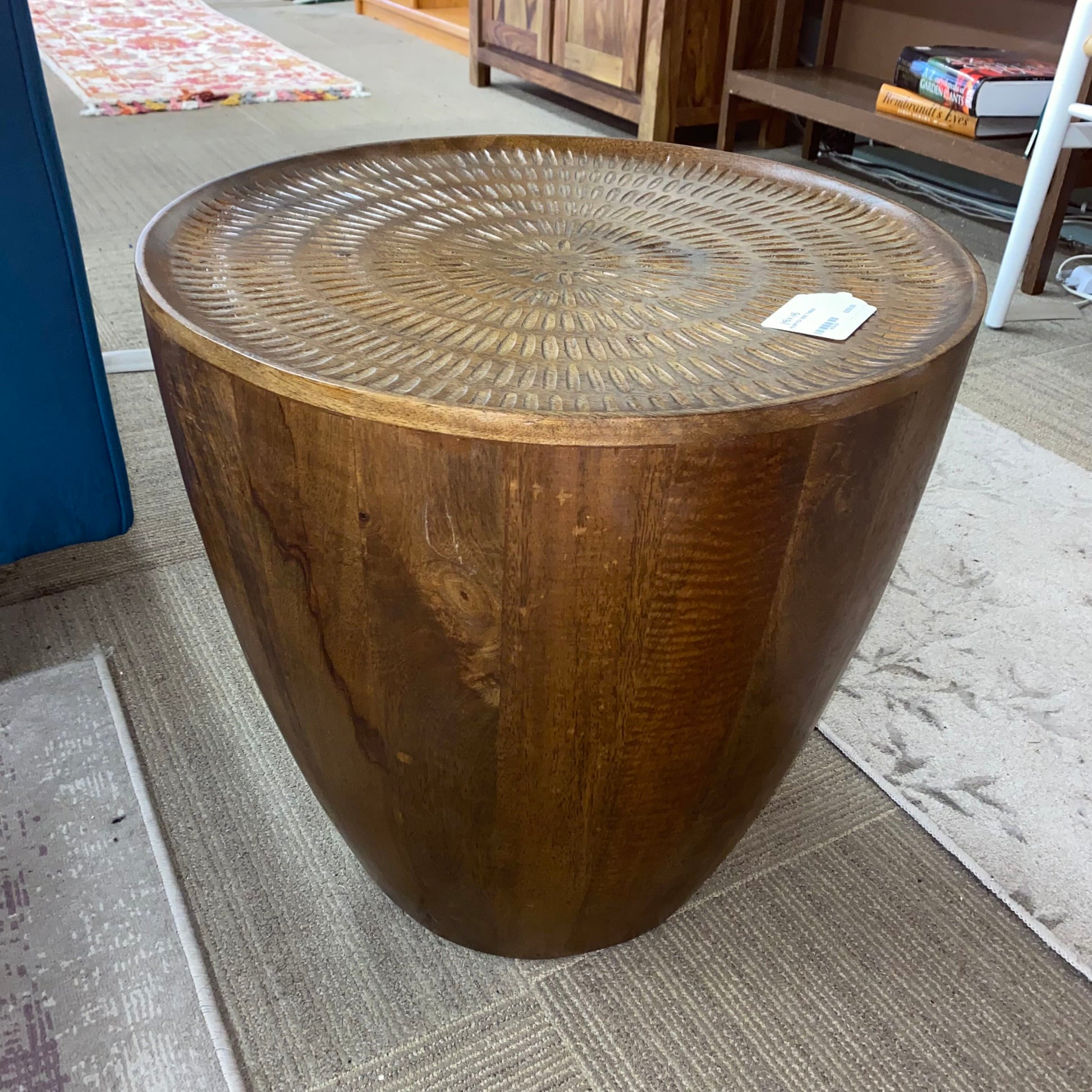 Wooden side table with textured surface on a carpeted floor