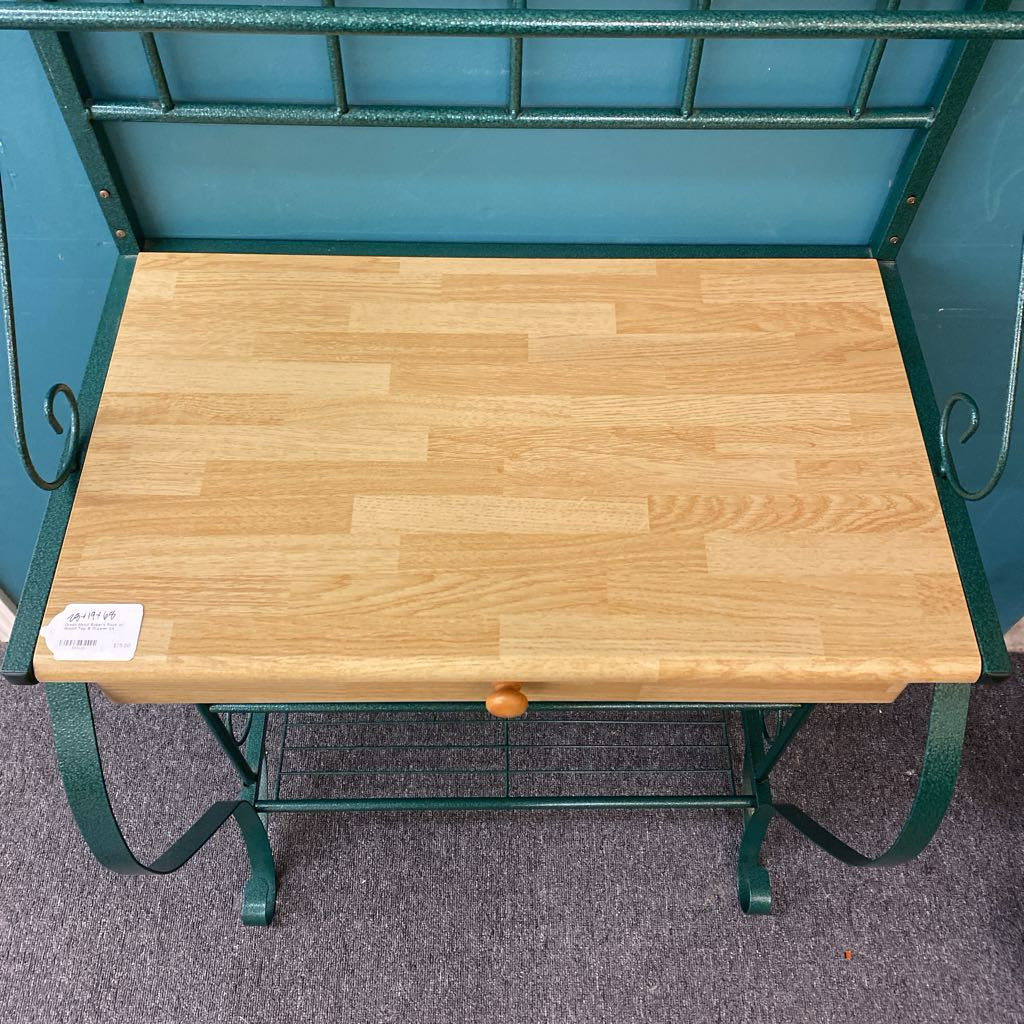 Wooden table with green metal frame on a gray floor
