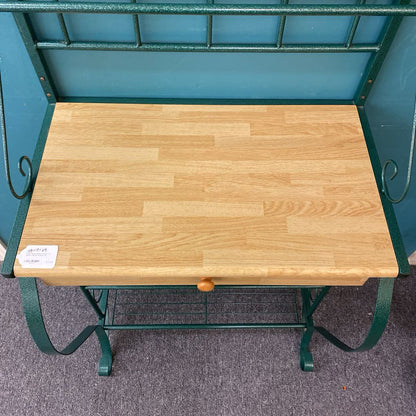 Wooden table with green metal frame on a gray floor