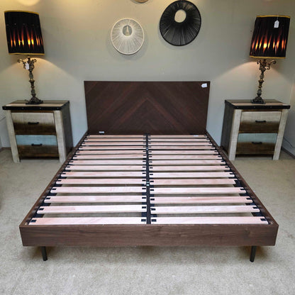 Wooden bed frame with slatted design in a room setting.