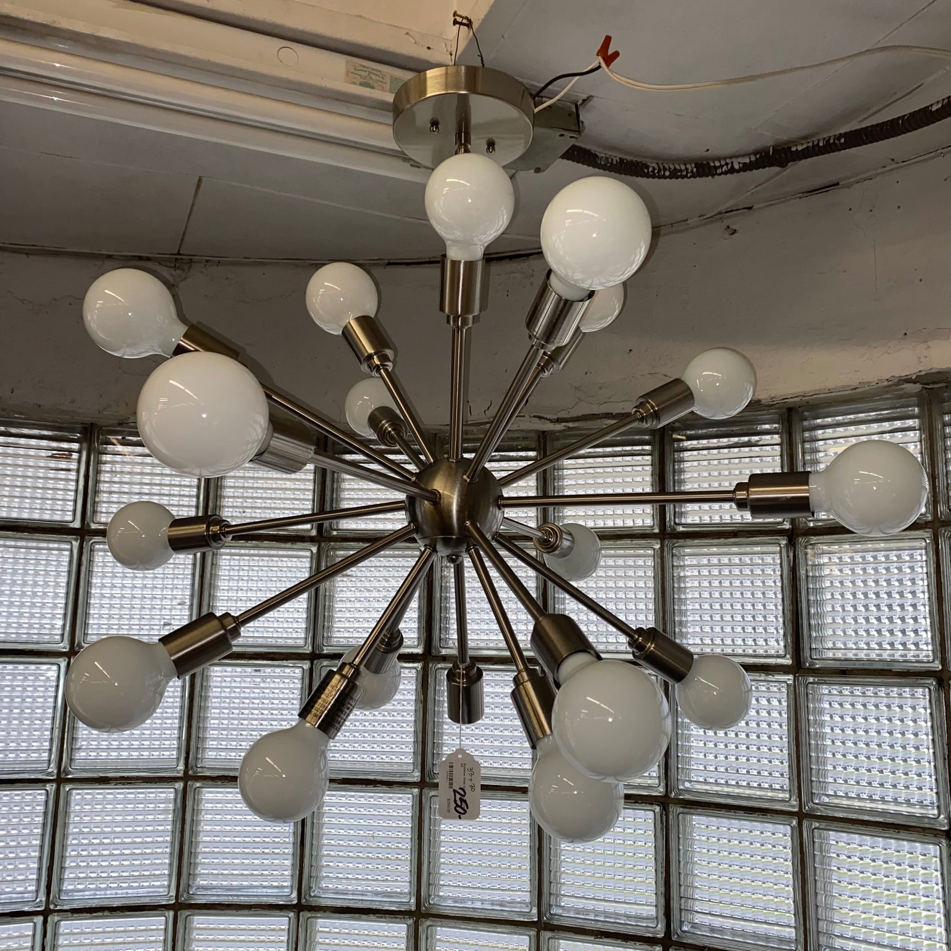 Chandelier with multiple light bulbs in a room with glass block walls.
