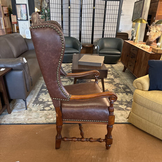 Brown leather armchair with wooden legs in a furniture store setting