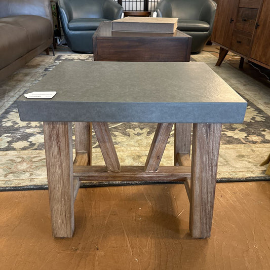 Coffee table with wooden legs and a gray concrete top in a living room setting.