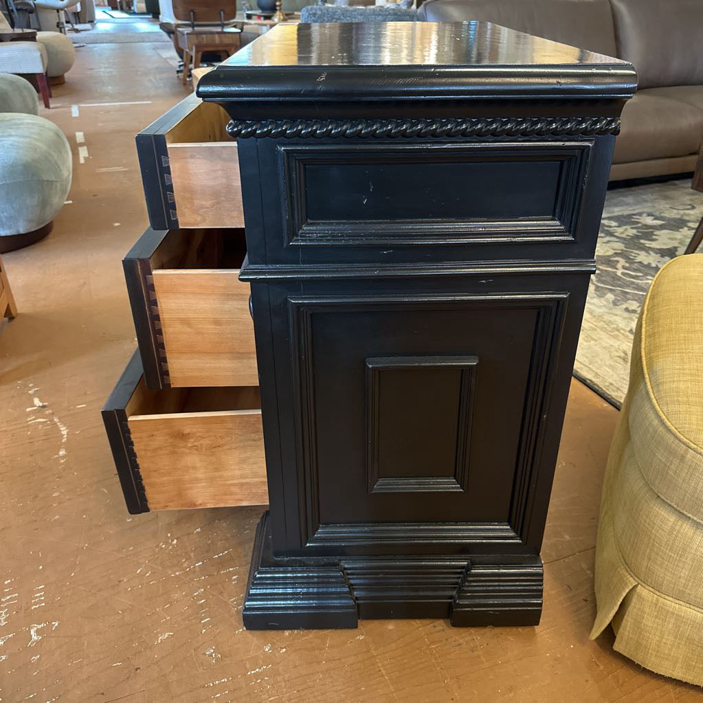 Black wooden nightstand with a drawer open in a furniture store setting