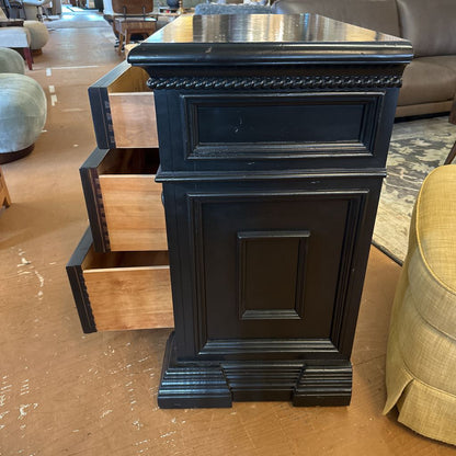 Black wooden nightstand with a drawer open in a furniture store setting