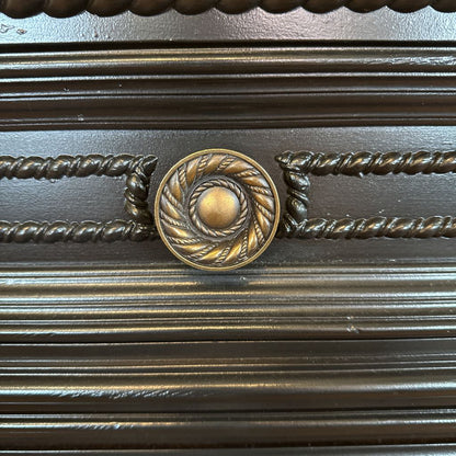 Decorative metal panel with a central circular design and twisted rope patterns.